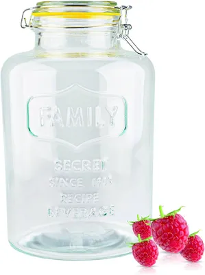 A clear glass jar with a yellow lid and a few raspberries next to it.