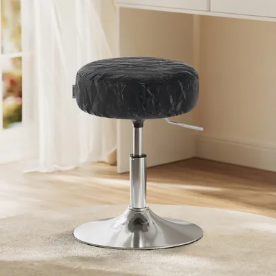 A black stool with a silver base is shown in a well-lit room with a window and curtains in the background.