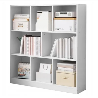 A white, multi-compartment bookshelf filled with books, boxes, and decorative items.