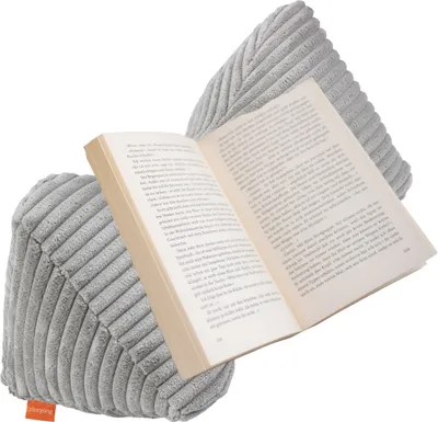 A gray corduroy book pillow holding open a book.