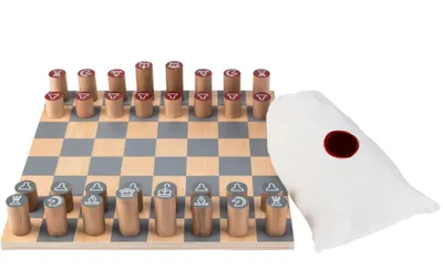 A wooden chess set with cylindrical pieces on a checkered board, next to a white drawstring bag with a red circle.