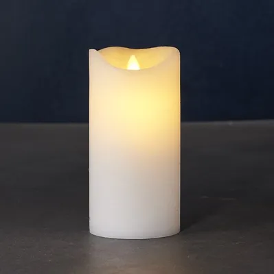 A white LED candle with a flickering yellow flame sits on a dark surface against a dark blue background.