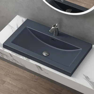 A modern bathroom sink with a chrome faucet and drain, set on a marble countertop.