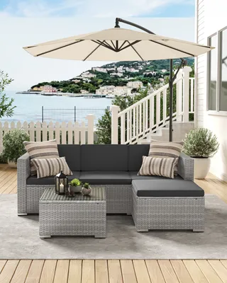 An outdoor patio scene with a sectional sofa, coffee table, and umbrella overlooking a coastal town.