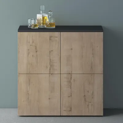 A wooden cabinet with a black top, featuring two glass bottles and two glasses with liquid on top.