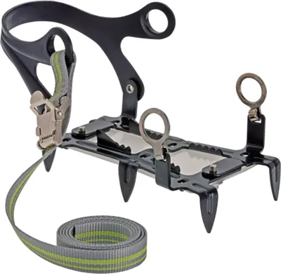 A close-up studio shot of a pair of black crampons with a gray and green strap.