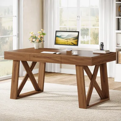 A wooden desk with a computer and flowers in a bright room.