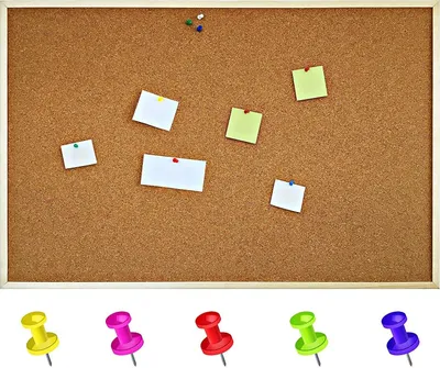 A cork bulletin board with several notes pinned to it, and five pushpins displayed below.