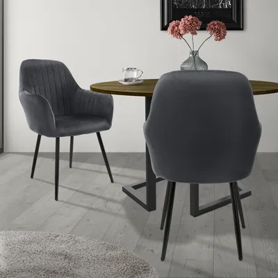 Two dining chairs are placed around a round wooden table in a room.