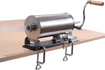 A stainless steel sausage stuffer clamped to a wooden table.
