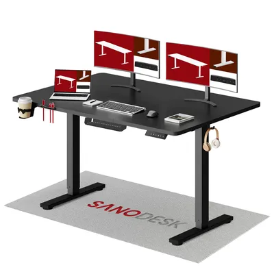 A black standing desk with multiple monitors, a laptop, keyboard, mouse, cup holder, and headphones. A mat with the brand name is on the floor.