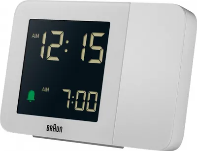 A white Braun digital alarm clock with a black screen displaying the time and alarm settings.