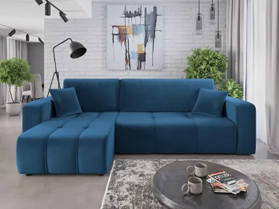 A modern living room with a blue sectional sofa, abstract art on the wall, and a coffee table with mugs and magazines.