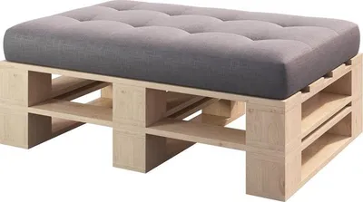 A close-up shot of a wooden pallet ottoman with a gray tufted cushion.
