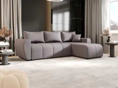 A modern living room with a gray sectional sofa, decorative pillows, and a side table.