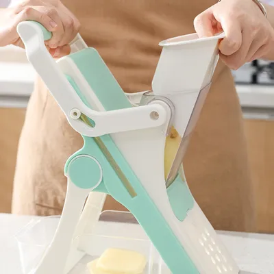 A person is using a vegetable slicer to cut a potato.