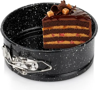 A slice of chocolate cake is placed inside a black springform pan with a speckled granite coating.