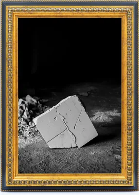 A framed image of a broken concrete block on a dark, textured surface.