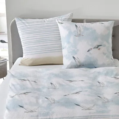 A neatly made bed with bedding featuring a seagull print.
