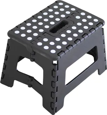 A black folding step stool with white dots on the top surface, shown from a slight angle against a white background.