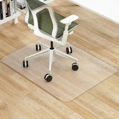 A clear office chair mat on a wooden floor in front of a bookshelf and an office chair.