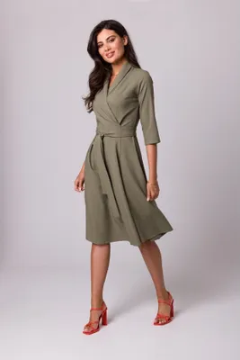 A woman is posing in a studio setting wearing a dress.