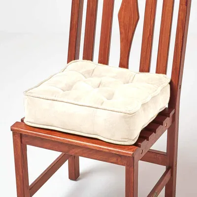 A cream-colored seat cushion on a wooden chair.