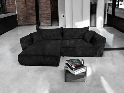 A modern living room with a black sectional sofa and a stack of books on a small table.