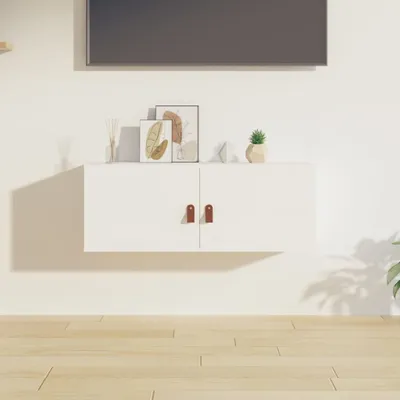 A floating white cabinet with two brown handles against a white wall.