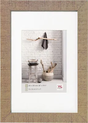 A framed picture of a rustic interior scene with a stool, basket, and decorative branches.
