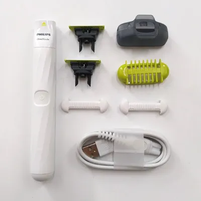 A flat lay of a Philips OneBlade grooming kit and its accessories on a white background.