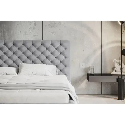 A modern bedroom with a tufted headboard bed and a concrete wall.
