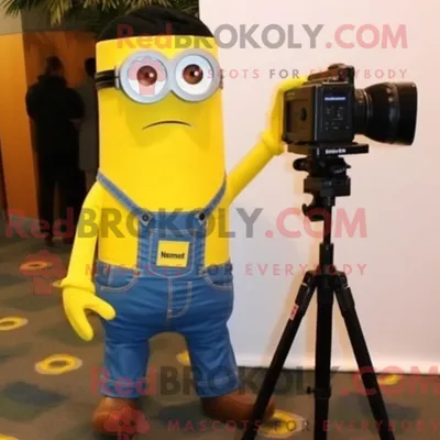 Immagine prodotto di Personaggio in costume mascotte REDBROKOLY fotocamera gialla vestito con jeans bootcut e fermacravatta