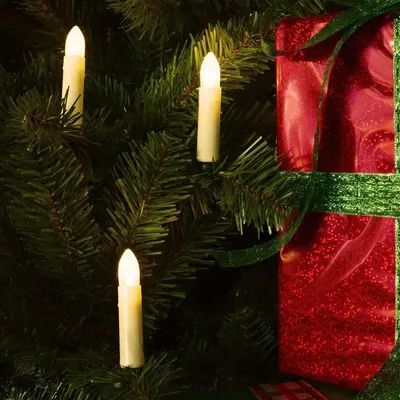 Close-up of LED candle lights and a wrapped gift on a Christmas tree.