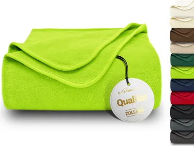 A folded green fleece blanket with a circular tag attached.