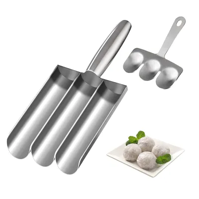 A stainless steel meatball maker with three tubes and a spatula, along with a small plate of meatballs and mint leaves, on a white background.