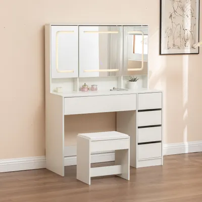 A white vanity table with LED lights, mirrors, drawers, and a stool, set against a light pink wall and wooden floor.