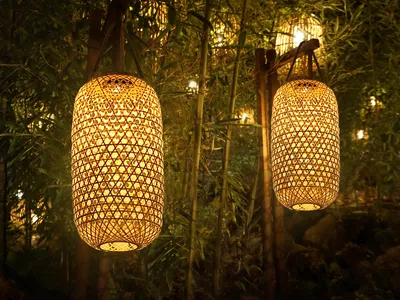 Two bamboo lanterns hanging in a bamboo forest at night.
