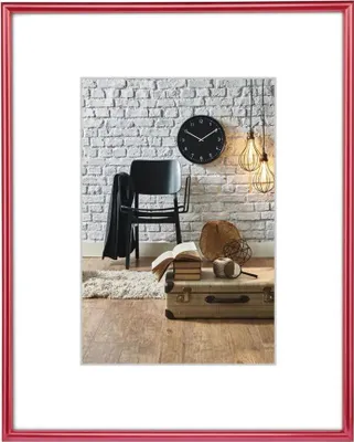 A framed picture of a room with a chair, clock, and suitcase.
