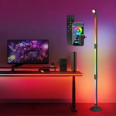 A gaming setup with a desk, monitor, and a floor lamp with RGB lighting.