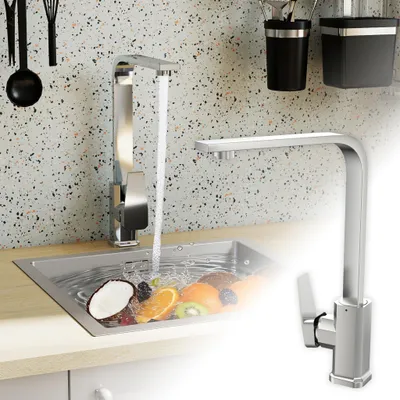 A kitchen sink with a faucet running water and fruit in it, with a second faucet shown in the foreground.