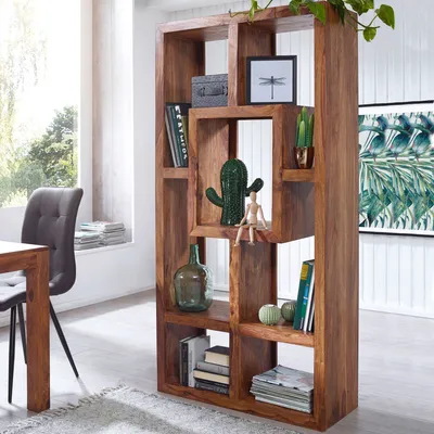 A wooden bookshelf filled with books and decorative items in a well-lit room with a large window.