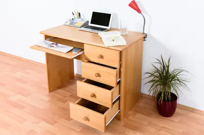 A wooden desk with a laptop, calculator, and a plant.