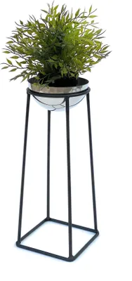A green artificial plant in a silver and black pot on a black metal stand.