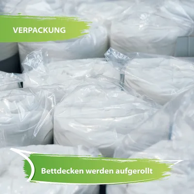 A pile of white duvets rolled up and sealed in clear plastic packaging.
