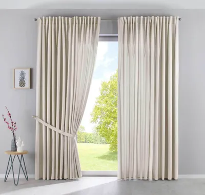A room with a large window covered by beige curtains.