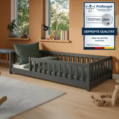 A child's bed with protective rails in a room with orange walls and a window.