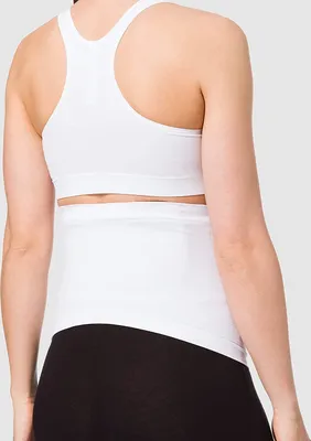 Rear view of a woman wearing a white sports bra and a white belly band over black leggings.