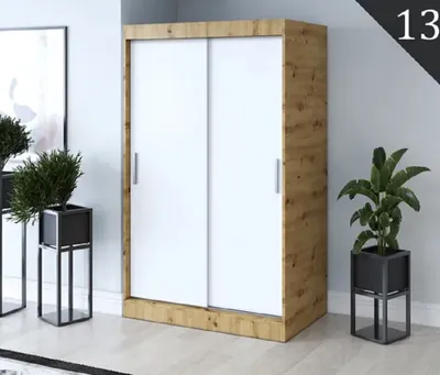 A sliding door wardrobe with white doors and a wood-grain frame, placed in a room with potted plants.