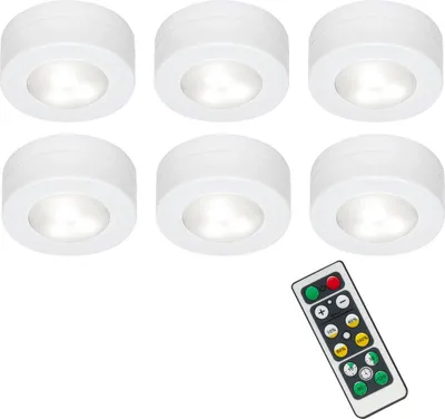 Six white LED puck lights are arranged in two rows of three, with a remote control positioned in the bottom right corner.